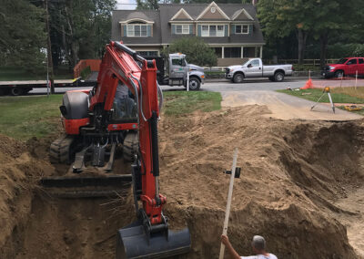 Excavator digging large hole residential neighborhood